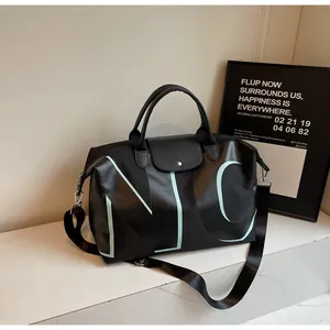 Detail of black large travel bag with snap closure and adjustable wide fabric strap
