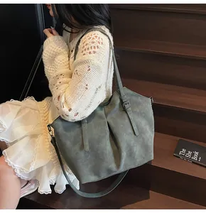 Detailed view of vintage green leather tote bag with long straps on wooden stairs