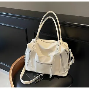 Dettaglio della borsa tote in pelle grana avorio con zip metalliche e nappine lunghe