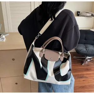 Detail of large travel bag with NYC letters, brown leather handles, and wide shoulder strap