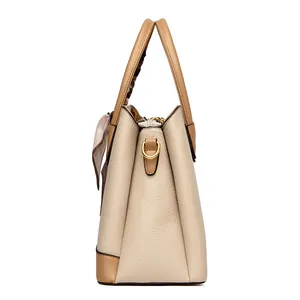 Beige litchi leather handbag with brown trim and floral scarf from a side perspective