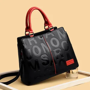 Black pebbled leather tote bag with red handles and embossed lettering for women