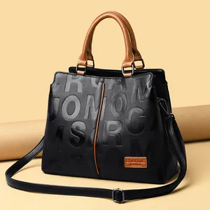 Classic black and brown leather handbag with adjustable strap for women in studio setting