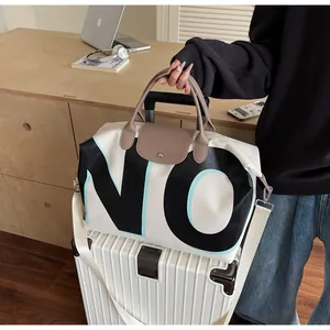 Detail of large travel duffel bag with letter print placed on a white suitcase