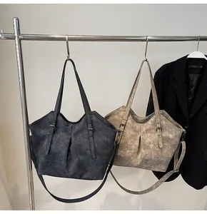Detail of vintage matte leather tote bags featuring pleated design and adjustable straps