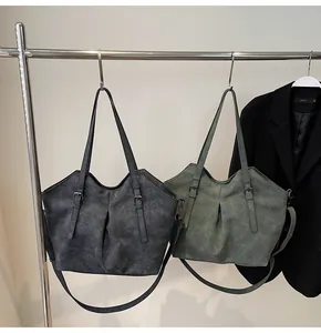 Close-up of matte faux leather tote bags in dark grey and green with vintage metal hardware