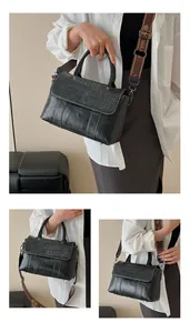 Dettaglio borsa nera con trama a coccodrillo, cuciture a contrasto e tracolla jacquard larga