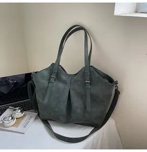 Detailed view of green matte tote bag featuring stylish buckle straps and pleated leather