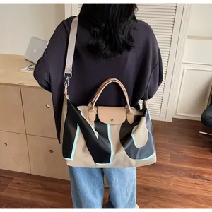 Detailed back view of a large beige travel tote with black NY letter print and wide strap