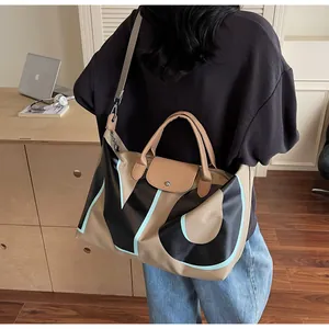 Detail of a large khaki travel bag with leather handles and blue letter print accents