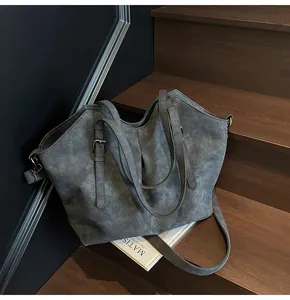 Close-up of vintage tote bag with adjustable strap and matte leather texture on stairs