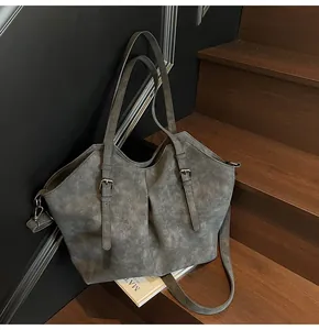 Detail of grey vintage matte tote bag with adjustable straps on dark wooden stairs