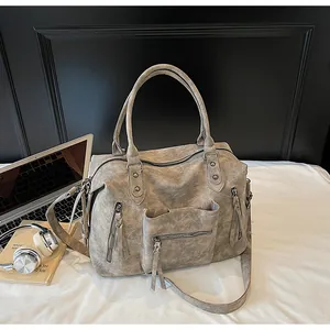 Detail of vintage large tote bag with multiple zippers and textured leather on white bed