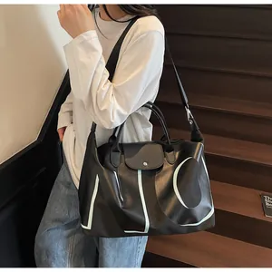 Detail of black leather tote bag with green letters and detachable nylon shoulder strap