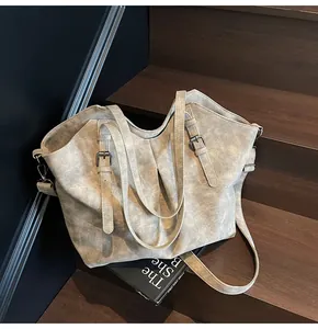 Detail of vintage matte faux leather tote bag with decorative buckles on a wooden staircase