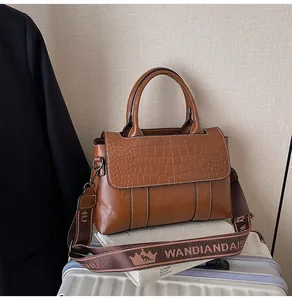 Borsa marrone con goffratura a coccodrillo e ampia tracolla in tessuto con logo ricamato