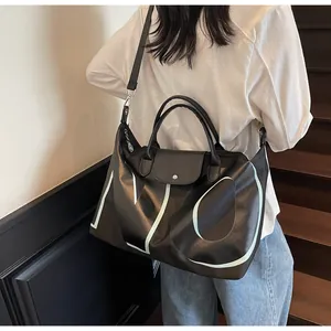 Macro shot of large black leather travel tote with white letters and shoulder strap