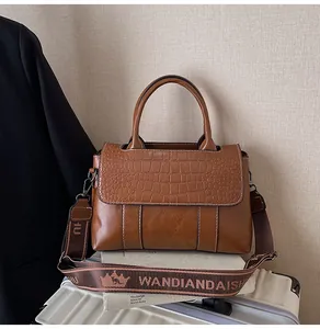 Dettaglio della borsa marrone vintage con trama coccodrillo e ampia tracolla a motivi