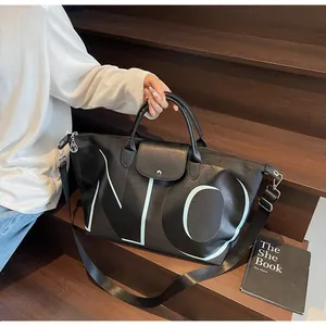 Close-up of black travel bag with white NO lettering and adjustable shoulder strap