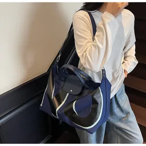 Detailed view of large navy tote bag with geometric patterns and leather accents worn by model