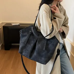 Vintage dark grey matte tote bag with adjustable strap worn with a beige trench coat