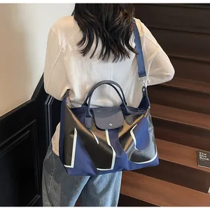 Detail view of large navy blue travel tote with leather handles and wide shoulder strap