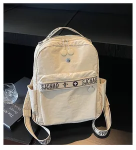 Detail of beige nylon backpack with SJCHAO lettering and side pocket on wooden surface