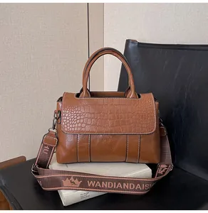 Dettaglio borsa a mano marrone con stampa coccodrillo e tracolla larga in jacquard
