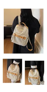 Detail view of cream travel backpack with orange decorative straps and multi-pocket design