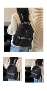 Detail of minimalist black nylon backpack featuring white lettered straps and side pockets