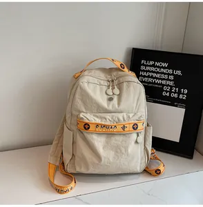 Detail of beige nylon backpack with orange straps and blue star patterns for daily use