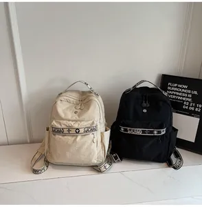 Detail of minimalist nylon backpacks in beige and black with stylish lettered webbing