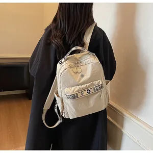 Rear view of model wearing a minimalist beige nylon backpack with large zipper pocket
