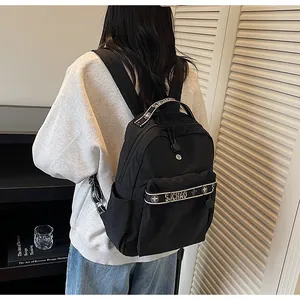Minimalist black nylon backpack featuring white logo straps and floral pattern details