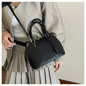 Dettaglio della borsa a mano nera a conchiglia indossata con accessori dorati