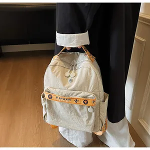 Detail view of cream casual backpack with orange straps and floral pattern branding