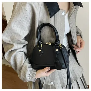 Dettaglio borsa a conchiglia in pelle nera martellata con accessori metallici dorati