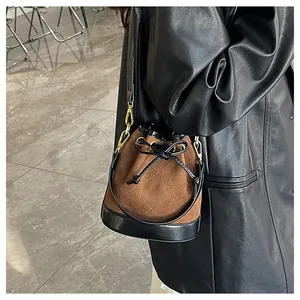 Détail du sac seau matelassé en daim marron et cuir noir avec des finitions dorées chic