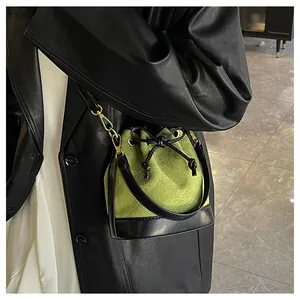 Détail du sac seau matelassé vert avec bordure en cuir noir et nœud de serrage élégant