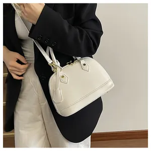 Borsa a conchiglia in pelle bianca con dettagli dorati indossata da una modella