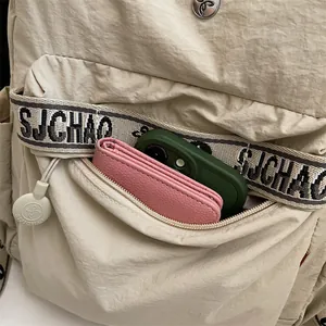 Minimalist beige travel backpack for women with lettered strap and durable nylon fabric