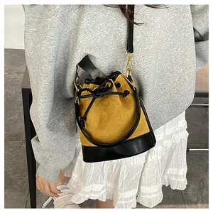 Détail du sac seau bandoulière en daim gingembre avec finitions en cuir noir et cordon