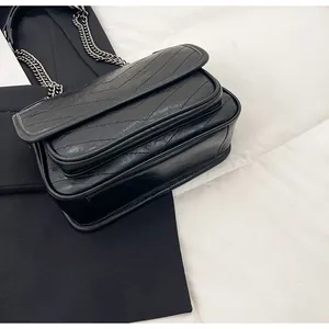 Dettaglio della borsa vintage nera in pelle plissettata con cuciture a V e catena
