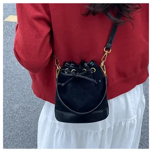 Détail du sac seau noir à cordon avec boucles dorées porté par un mannequin en extérieur