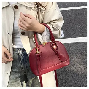 Dettaglio di borsa a mano rosso scuro in pelle testurizzata con accessori metallici dorati