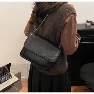 Dettaglio macro della borsa a tracolla in pelle vintage nera con impunture chevron e catena