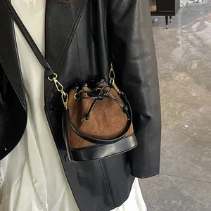 Sac seau chic en daim marron matelassé avec détails dorés porté par un mannequin