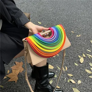 Detail der beigen geflochtenen Umhängetasche mit buntem Regenbogen-Griff im Freien