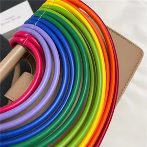 Detail der bunten gewebten Griffe an einer minimalistischen cremefarbenen Umhängetasche