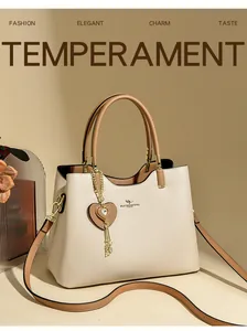Detail of beige leather handbag featuring a kangaroo metal logo and heart tassel charm